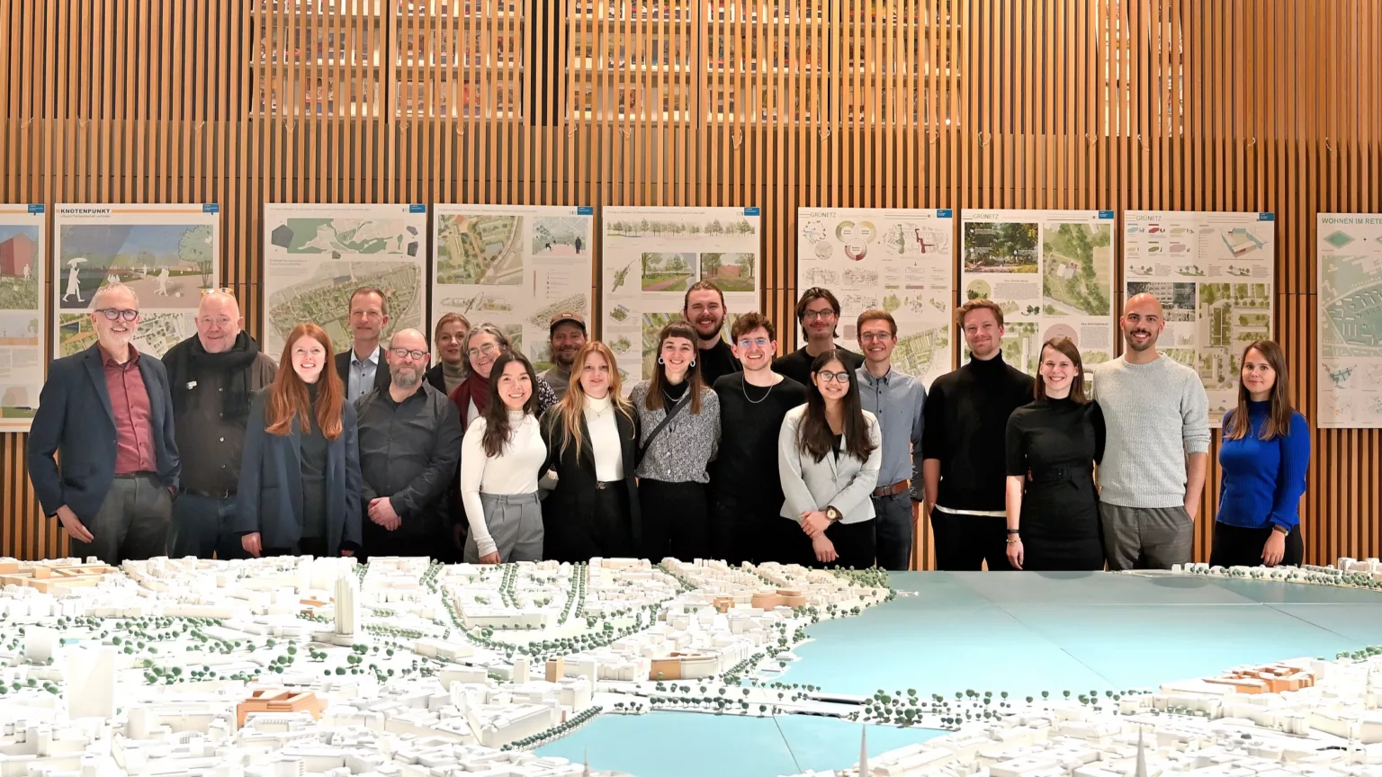 Gruppenfoto der Preisträger*innen des Otto-Linne-Preises 2023 vor ausgestellten Wettbewerbsplänen und einem großen Stadtmodell.