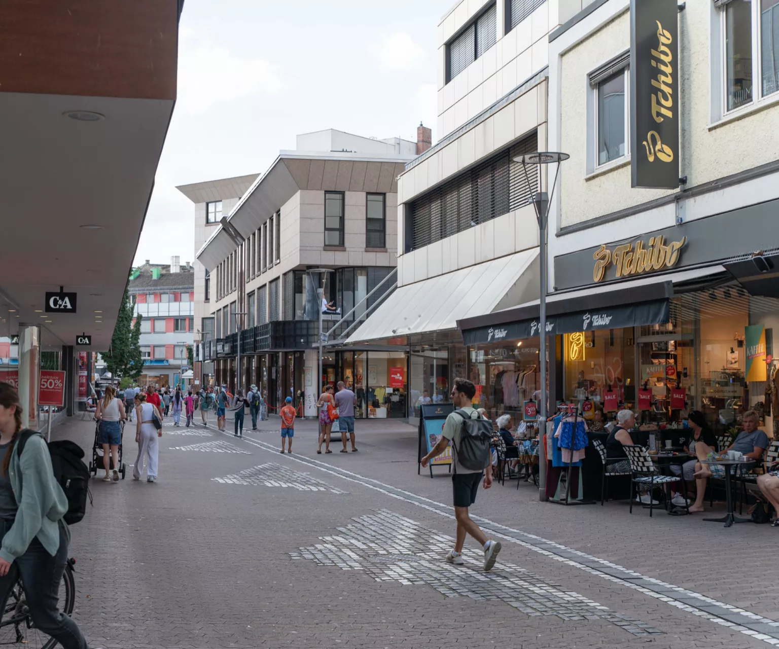 Bild einer typischen Innenstadtstraße mit einigen Passant*innen.